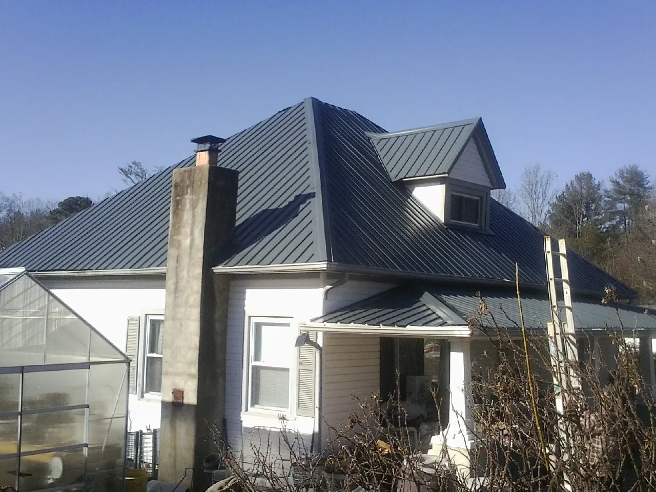 Dark blue standing seam metal roof on a white farmhouse with dormer — Slate & Tile Roof Repair by Roofing Brothers in Gravel Switch