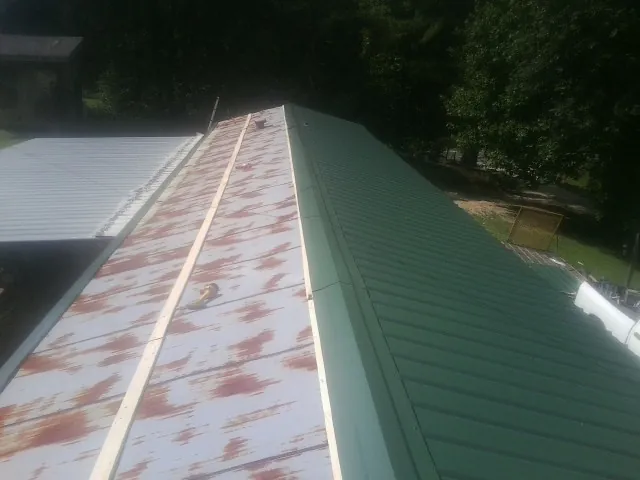 Old rusted panels beside newly installed green metal roofing — Wind Damage Roof Repair by Roofing Brothers in Gravel Switch