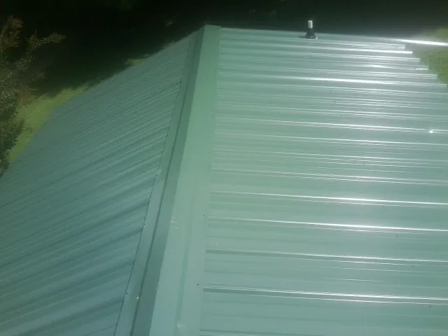 New green metal panels meeting at the ridge of a roof — Flat Roof Repair work by our crew in Gravel Switch