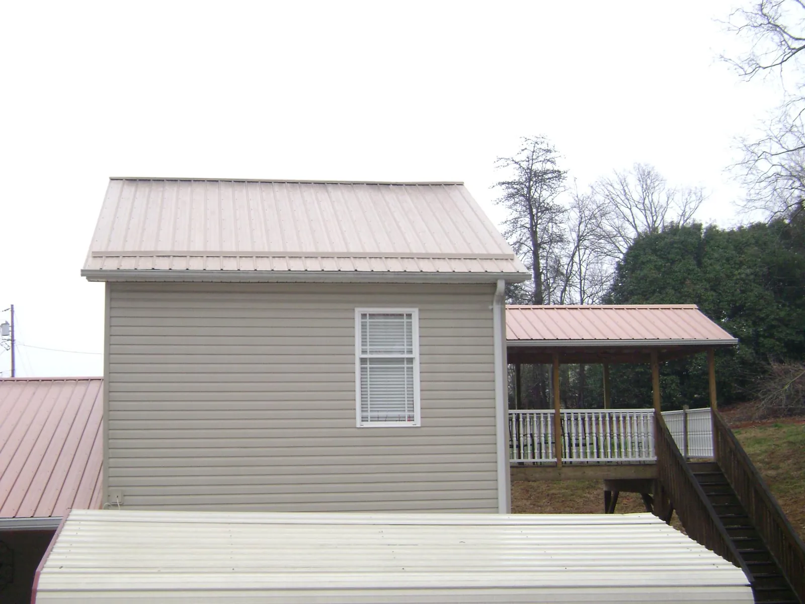 Tan metal roofs on a two story addition and attached porch, from a Roof Replacement job in Gravel Switch