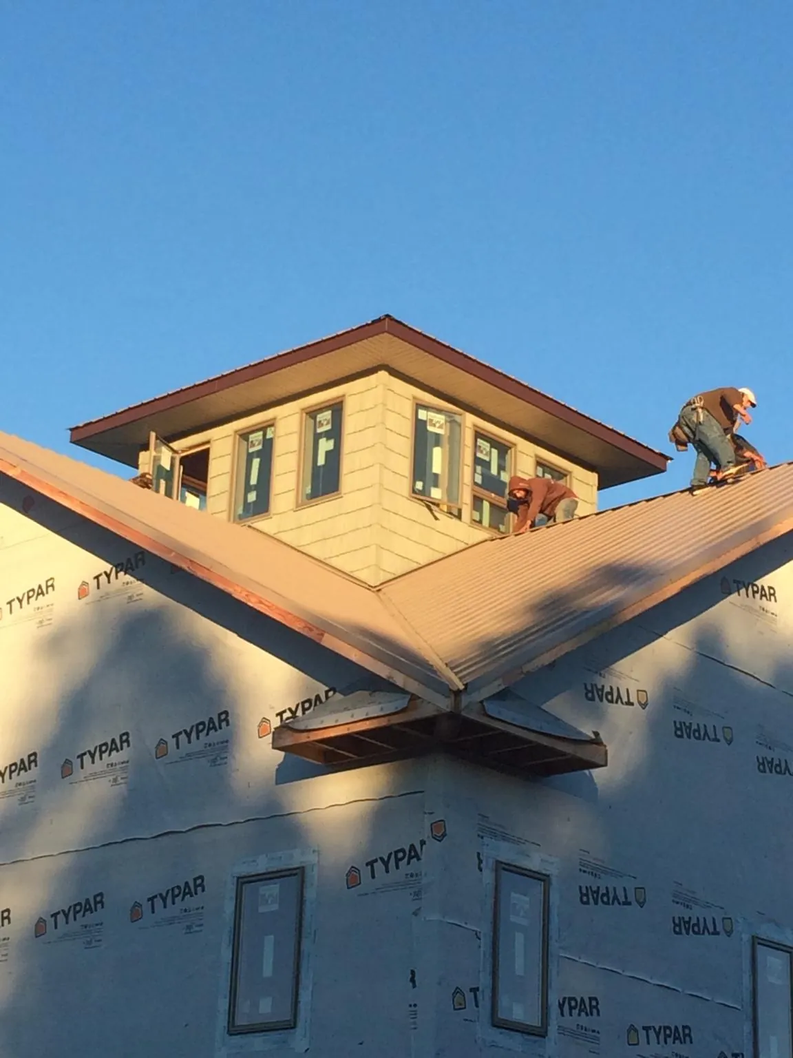 Roofers working around a rooftop cupola on a new metal roof at sunset — Roof Waterproofing in Gravel Switch by Roofing Brothers